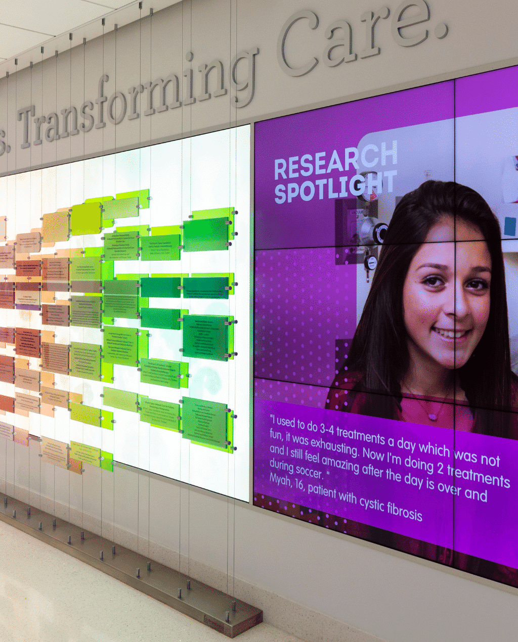 Digital donor wall 'Transforming Care' with green plates & featured female researcher