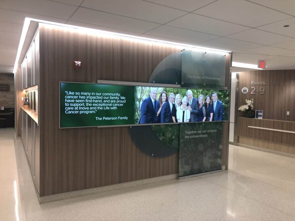 Philanthropic donor display at a hospital featuring a family and a quote about the impact of community support on cancer care